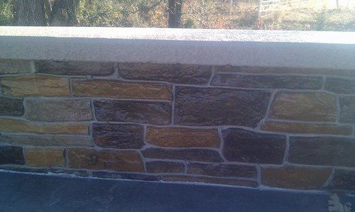 Form liner concrete wall, stamped pool deck with textured seatwall coping - Individually stained rocks along wall